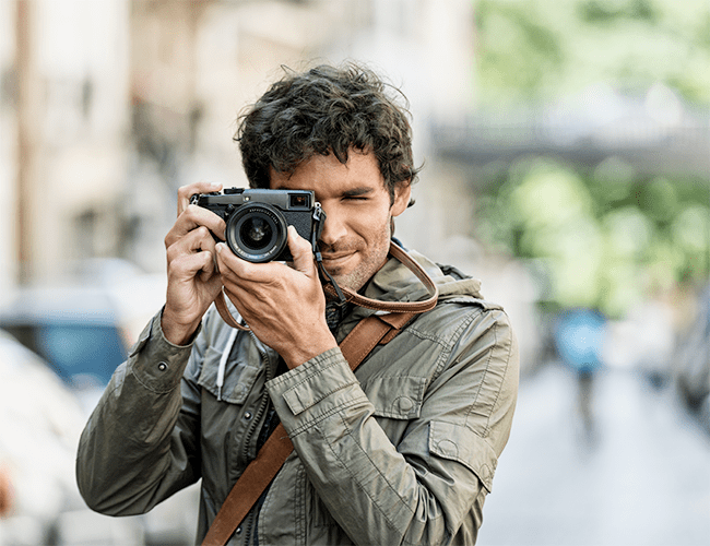 Young man focusing a camera thinking about his slow travel experience.