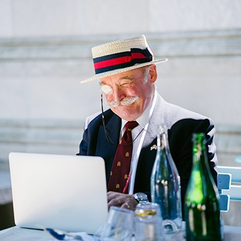 Elderly man in a straw hat on a laptop wondering if we still need SEO in 2021.