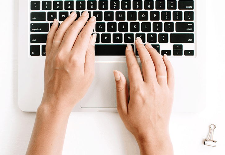 Hands typing on laptop keyboard.