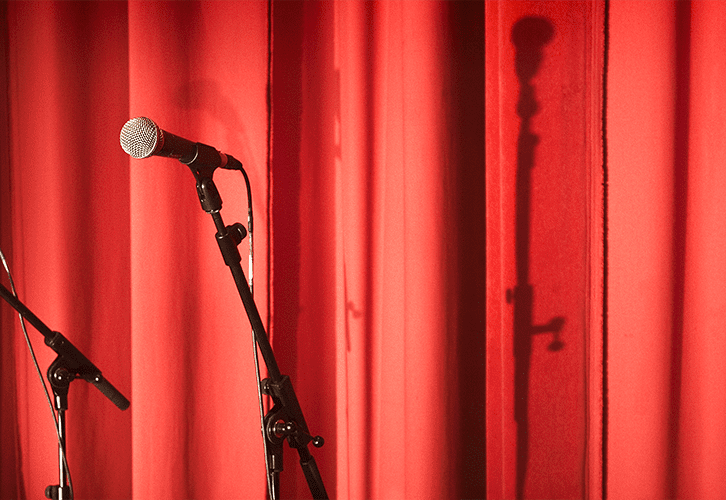 Red curtains and microphones waiting for a speech to be delivered
