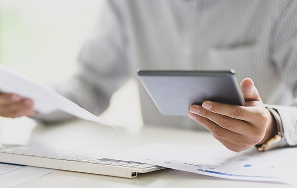 Man comparing paper report with figures on iPad - content marketing
